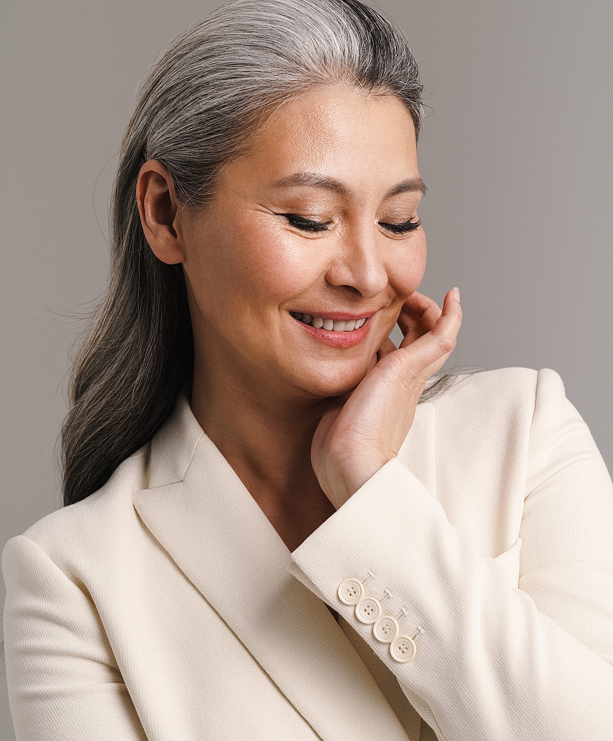 Smiling woman with gray hair in beige blazer.