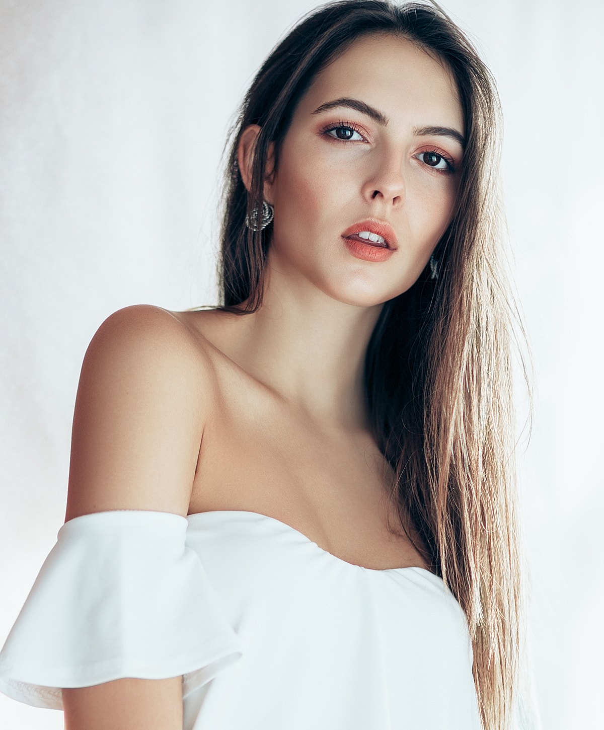 Woman in a white off-shoulder top, looking confidently.