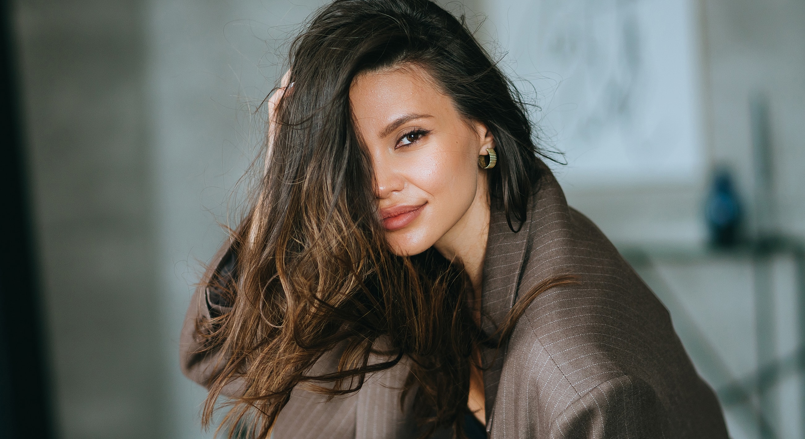 Woman with long hair smiling in a stylish outfit.