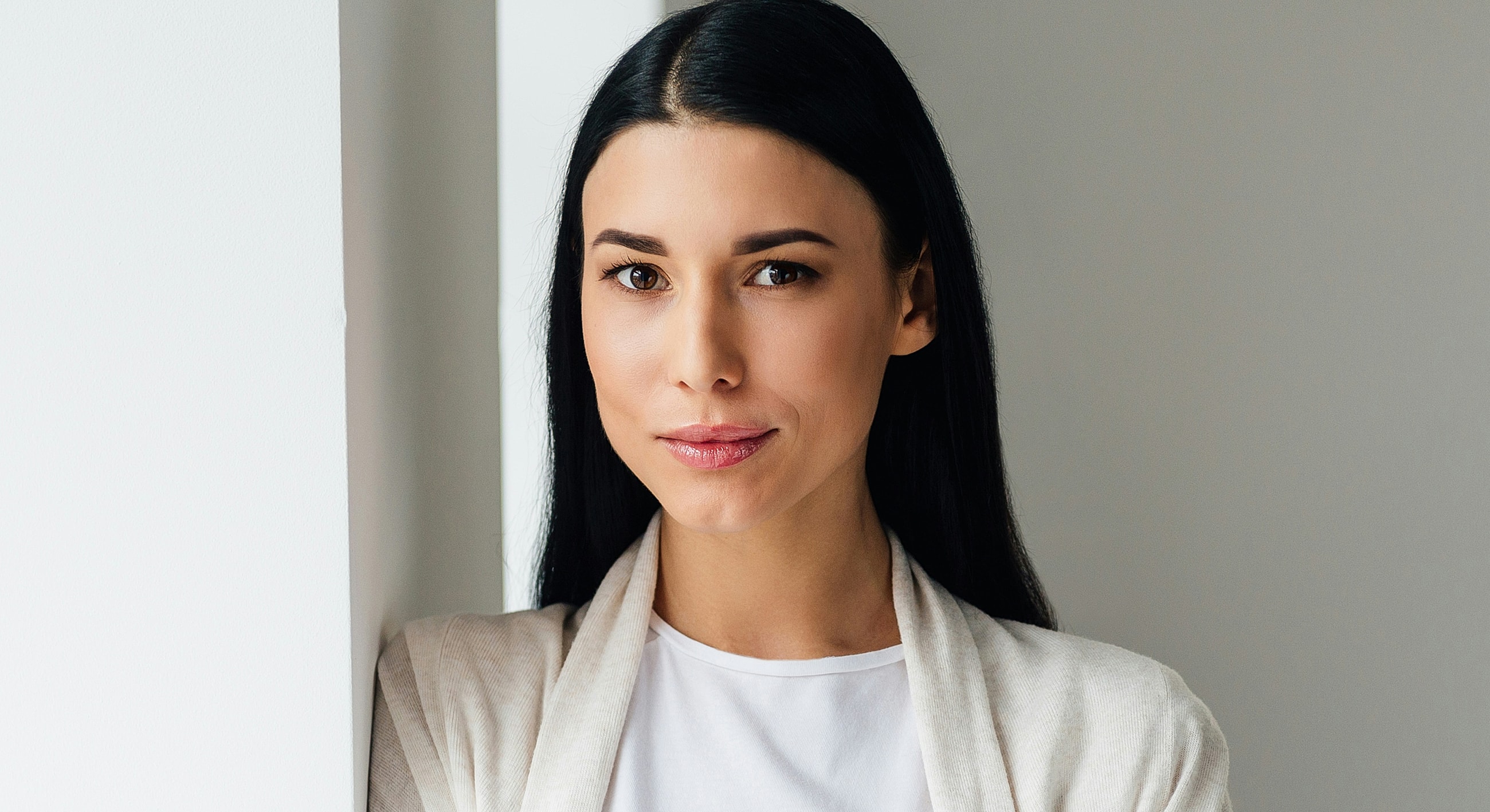 Woman posing against a light wall backdrop.